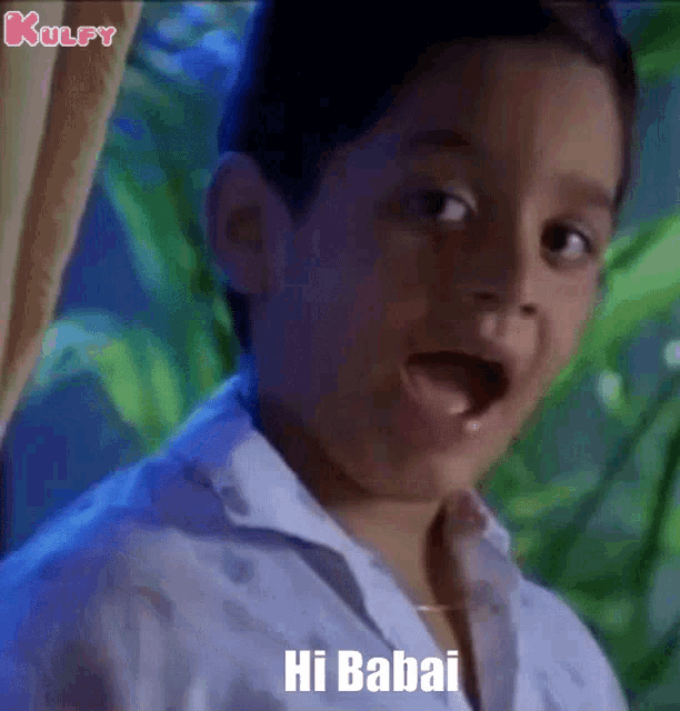 a young boy is saying hi babai with his mouth open .