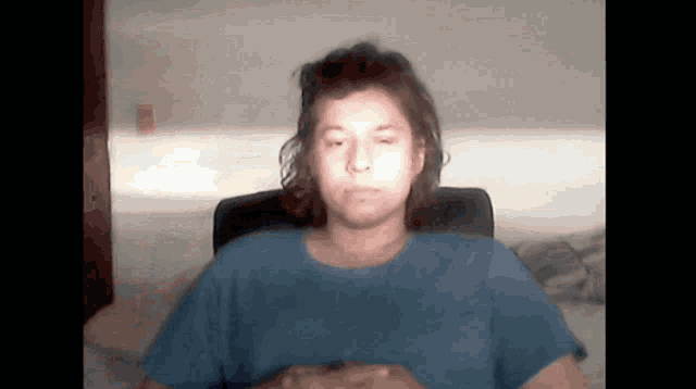 a woman in a blue shirt sits in a chair