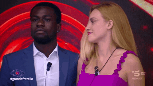 a man in a suit and a woman in a pink dress are on a television screen with the words grandefratello on it