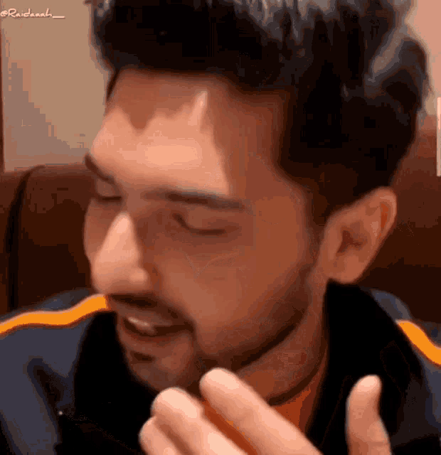 a man with a beard is sitting in a chair with his eyes closed and eating something .