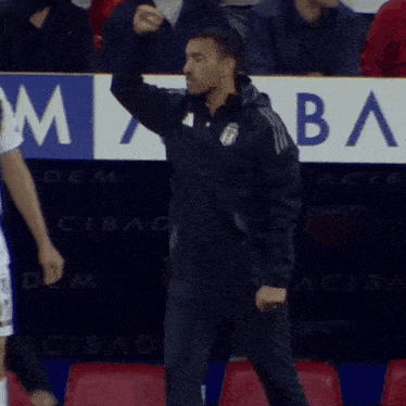 a man in a black jacket with the number 2 on it stands next to a man in a white shirt