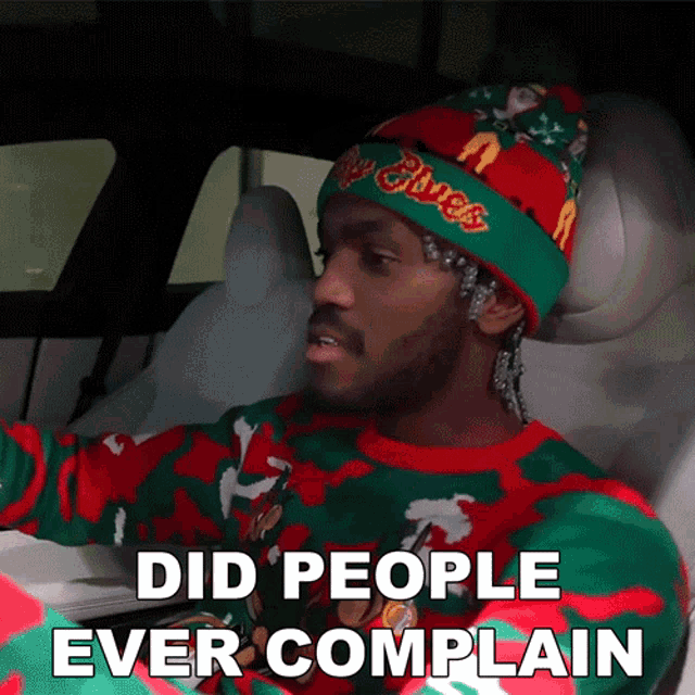 a man wearing a christmas sweater and a beanie says did people ever complain