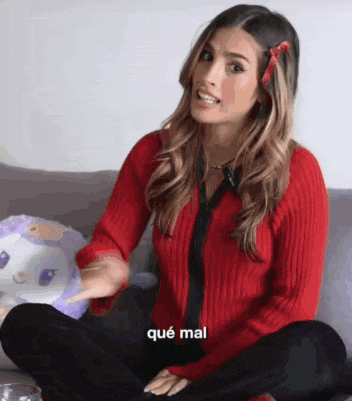a woman in a red sweater is sitting on a couch with her legs crossed