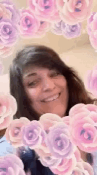 a woman is surrounded by pink and purple roses and smiling