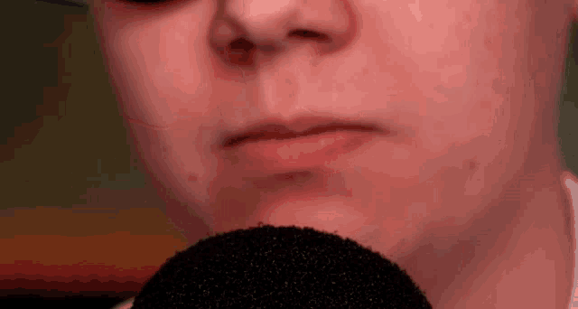 a close up of a person 's face with a black microphone in front of it .