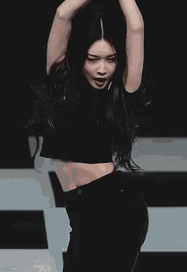 a woman in a black crop top is holding a microphone in her hand