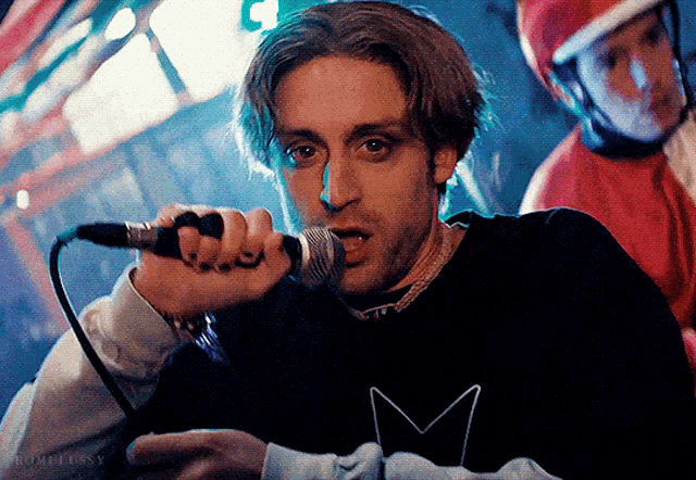 a man singing into a microphone with the letter m on it