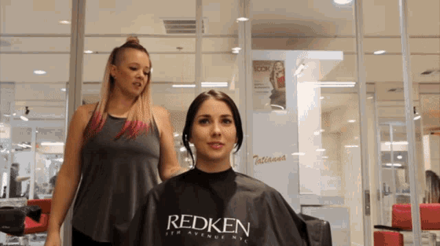 a woman is getting her hair cut by a redken hairdresser