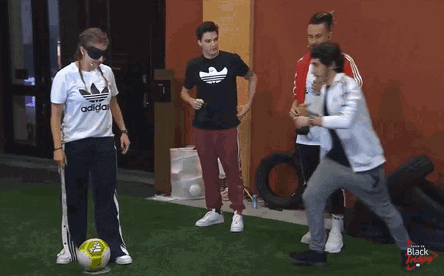 a group of people are playing with a soccer ball and one of them is wearing an adidas shirt