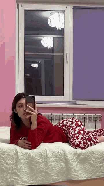 a woman is laying on a bed taking a picture of herself with her phone