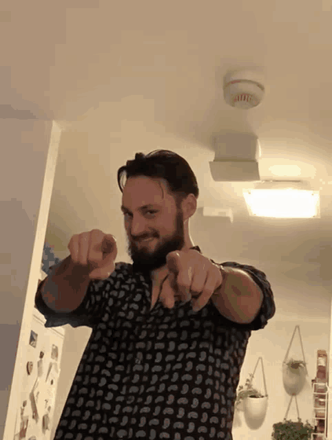 a man with a beard is pointing at the camera with both hands