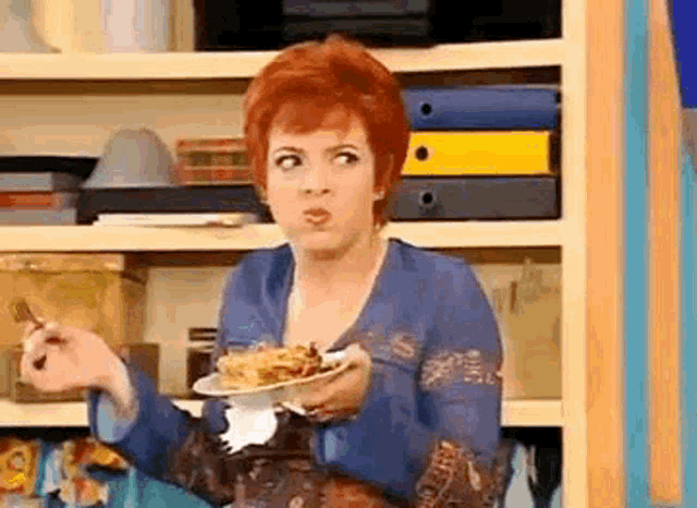 a woman with red hair is holding a plate of food and making a funny face .
