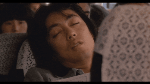 a man is sleeping on a plane while holding a piece of paper