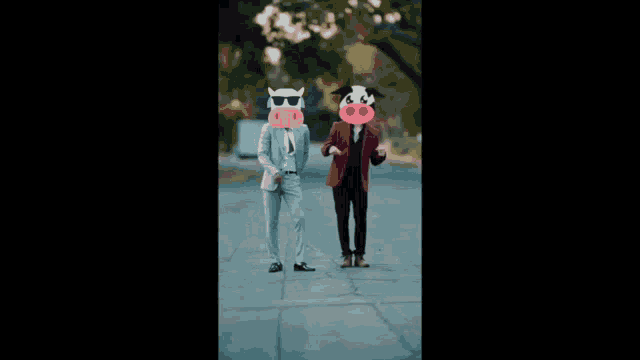 two men in suits with cow masks on their faces are running down the street