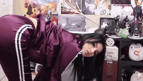 a woman in purple pants is laying on the floor in front of a shelf with stuffed animals on it