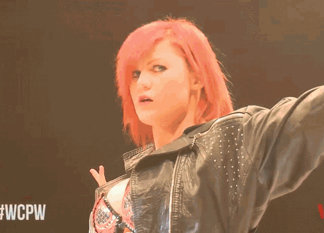 a woman with red hair is standing in front of a black background that says #wcpw