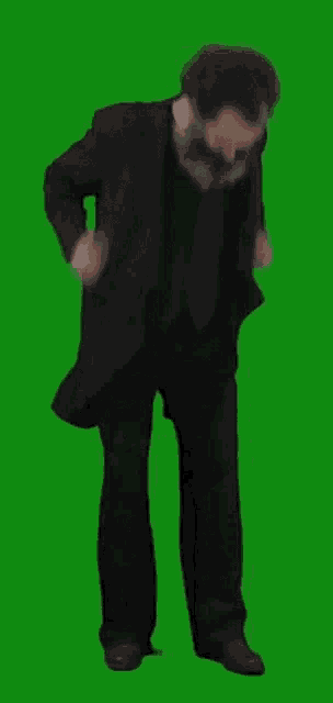 a man in a suit and tie is dancing on a green screen