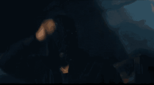 a man in a black jacket is sitting in a car at night .