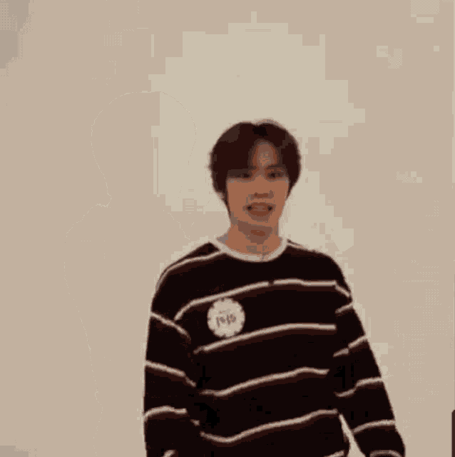 a man in a striped sweater is making a heart with his hands .