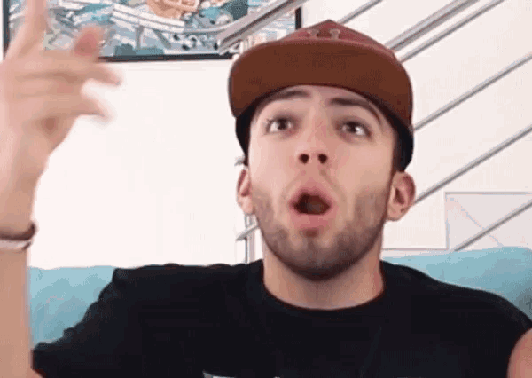 a man with a beard is wearing a hat and making a face