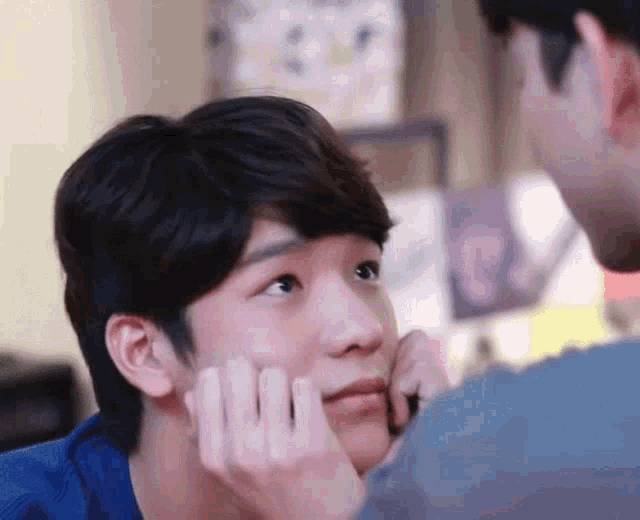 a man is touching another man 's face with his hands .
