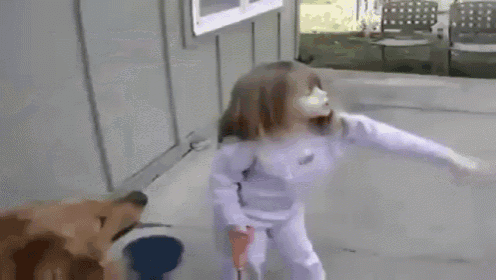 a little girl is standing next to a dog on a leash .