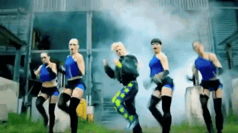 a group of women in blue outfits are dancing in a field