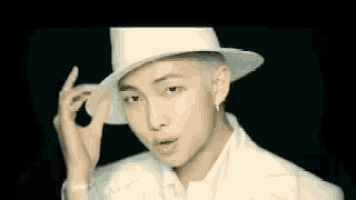 a young man wearing a white hat and a white suit .