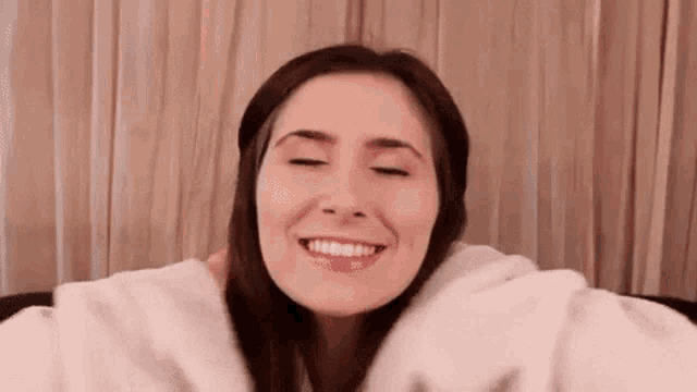 a woman is smiling with her eyes closed while sitting on a couch .