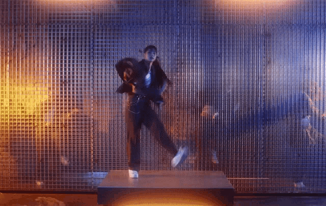 a man in a suit is dancing on a stage in front of a wall