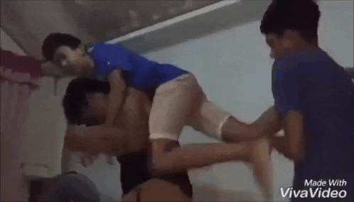 a man is carrying a child on his back in a room while two other men watch .