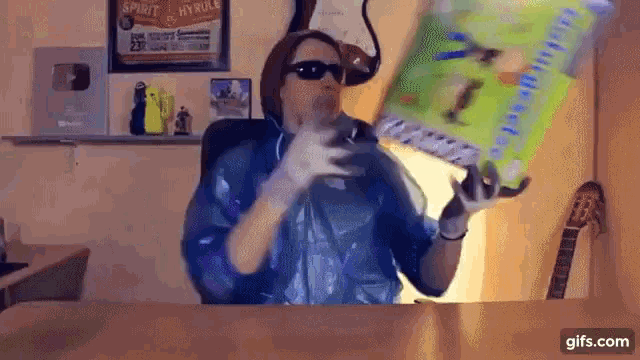 a person wearing sunglasses and gloves is holding a bag of cereal