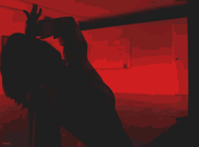 a woman is kneeling down in a dark room with a red light behind her and the word twice below her