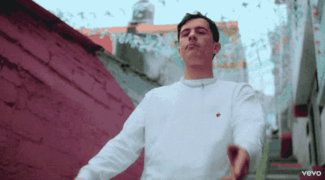 a man is wearing a white sweatshirt with a heart on it and the word vevo on the bottom right