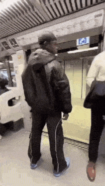 a man in a black jacket and black pants is standing on a subway train .