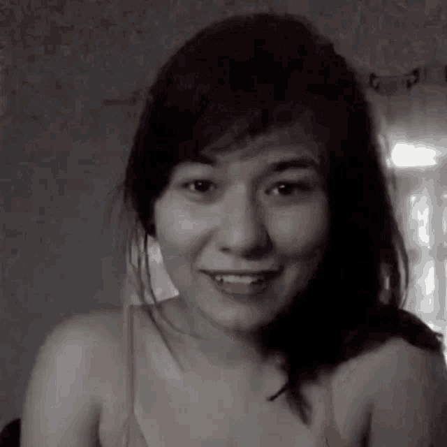 a black and white photo of a smiling woman in a bra