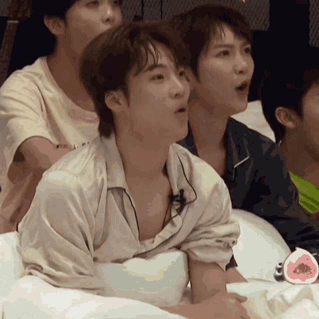 a group of young men are sitting on a bed and one of them is wearing a shirt that says i love you