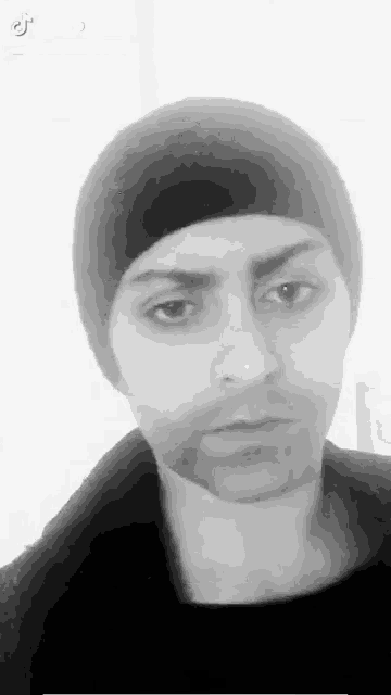 a man wearing a black beanie looks at the camera in a black and white photo