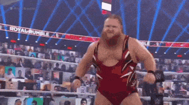 a bearded wrestler is standing in a wrestling ring with his fist in the air .