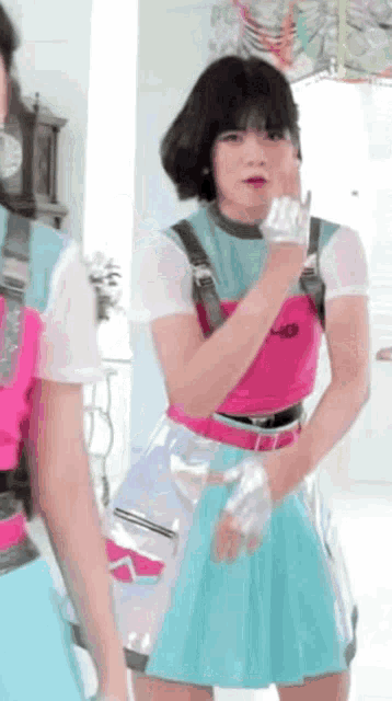 a girl in a pink top and a blue skirt is standing next to another girl in a pink top .