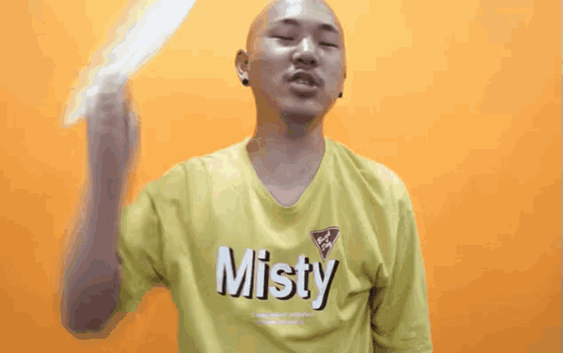 a man wearing a yellow shirt that says misty holds a fan