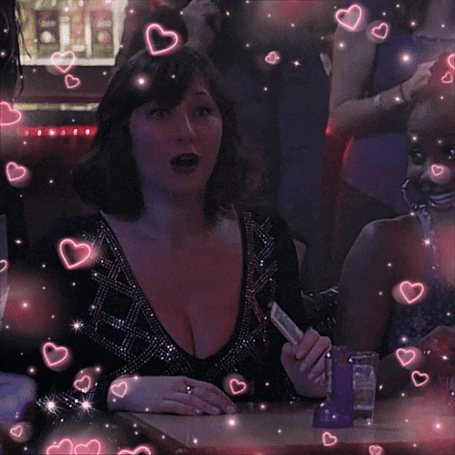 a woman sitting at a table with her mouth open and hearts around her