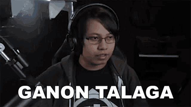 a man wearing headphones and glasses is sitting in front of a microphone in a dark room .