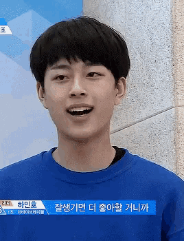 a young man wearing a blue sweater with korean writing on the front