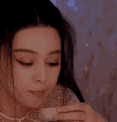 a close up of a woman drinking from a glass .