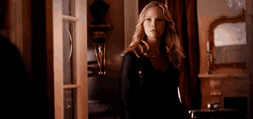 a woman is standing in a room in front of a door looking at the camera .