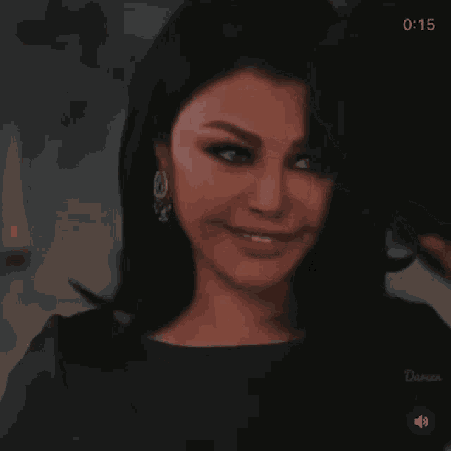 a woman in a black dress and earrings is smiling while looking at the camera .