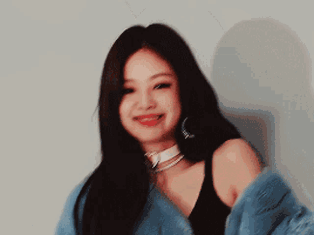 a woman wearing a black bra and a blue fur coat smiles