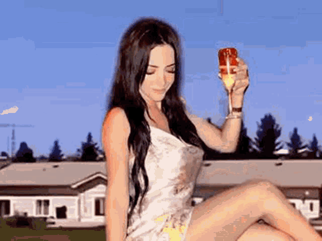 a woman in a white dress is holding a glass of champagne .