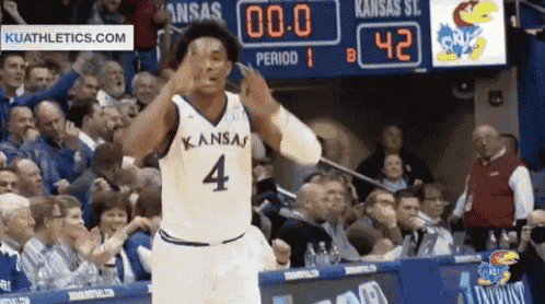 a basketball player wearing a kansas jersey number 4 stands in front of a crowd